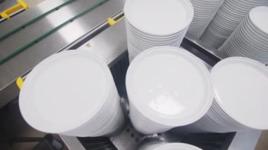 Yüksek miktarda temiz seramik plaka çelik kabın içinde üst görüşü kapatır. Lokantadaki bulaşık yıkama odasında bulaşık yığını var.