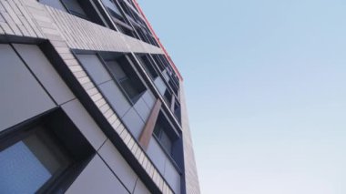 Mavi gökyüzü alçak açılı çekimin altında tuğla cephede camları olan ticari bir bina. Çağdaş şehir caddesindeki ofis merkezi