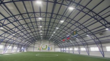 Parlak bir hangarda suni yeşil çimenliği olan büyük bir futbol sahası. Futbol antrenmanları için boş bir arena. Top oyun sahası