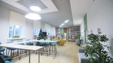 ALMATY, KAZAKHSTAN - 09 Şubat 2023: Noel ağacı yanında masa ve dinlenmek için rahat bir yer olan ofis yemek odası. Şirket çalışanlarının kapatılması harcamaları kırar