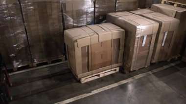 ALMATY, KAZAKHSTAN - 17 Nisan 2023: Forklift depoda folyoyla kaplanmış karton kutuları alır. Makine büyük bir karton kutu taşıyıcı