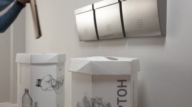 Adam binanın girişindeki çöp kutusuna karton çarşaf atıyor. İnsan, çevreyi yavaş çekim korumak için çöpü ayırır