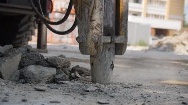 Hidrolik kırıcı şehir bölgesinde gevşer ve asfaltı kırar. Profesyonel ağır makineler eski beton kaplamayı yok ederek yeni bir yol kapatma sistemi oluşturuyor.