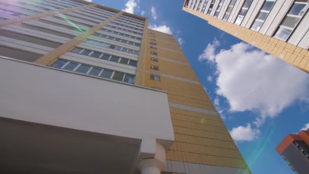 明るい太陽の下で白い積雲と青い空に対する高層ビル 日当たりの良い日に都市の現代住宅団地低角度ショット — ストック動画