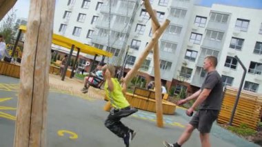 ALMATY, KAZAKHSTAN - 10 Mayıs 2023: babalar yerleşim alanının çocuk parkında salıncakta sallanıyor. Aileyle vakit geçirmek. Toprak inşa eden çocuklar için eğlence