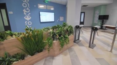 Ev bitkileri turnike turnikeleri ve antredeki duvarda büyük bir televizyon. Ofis merkezinin şık iç tasarımı