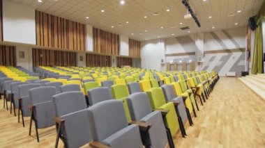 Boş konferans salonunda renkli katlanmış koltuklar. Parlak ışıklandırılmış oditoryumdaki konforlu seyirci yerleri