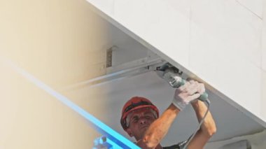 ALMATY, KAZAKHSTAN - 16 Mayıs 2023: İnşaatçı inşaat alanında metal kiriş kenarı kesiyor. İskeleler üzerinde çerçeve tutturma manuel elektrikli araç süreçlerine sahip işçiler