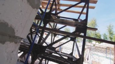 İnşaat alanının alçak açılı çekiminde köpük beton bina duvarı ile uzun tahtaları olan metal iskeleler. İnşaat ekipmanları ve malzemeler
