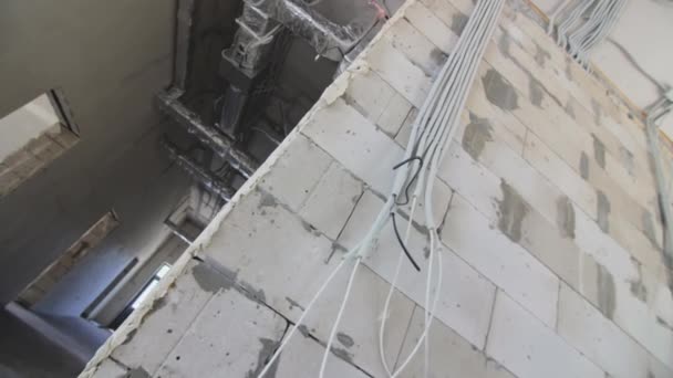 Ein Bündel Von Kabeln Hängt Einer Wand Aus Schaumstoffbetonsteinen Elektrische — Stockvideo