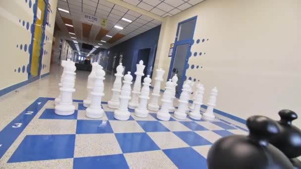棋盘放置在教育中心长廊的地板上 白种人和黑种人站在等候比赛的地方 — 图库视频影像