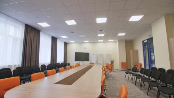 会议室配备长桌 舒适的橙色和黑色椅子 演讲台靠近写字板和等离子电视 — 图库视频影像