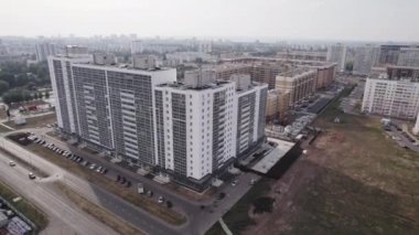 Konut bölgesinde park halindeki arabaları olan çok katlı bir apartman bloğu. Yol kenarında modern apartman binaları olan bir yerleşim yeri.