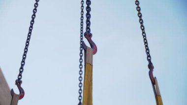 İnşaat alanında ağır yük kaldırmak için kule vinci. Tuğla yapıya ve mavi gökyüzüne karşı hareketli erektör vinç kancaları