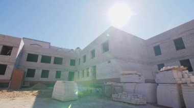 İnşaat alanındaki tamamlanmamış tuğla ev. Konut alanındaki beyaz tuğla bina için yığınla inşaat malzemesi.