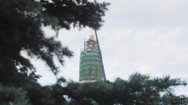 İnşaat işçileri inşaat kulesinin çatısına büyük bir yıldız yerleştiriyorlar. İnşaat vinci kış şehrinin çatısına yıldız kaldırıyor.