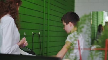 ALMATY, KAZAKHSTAN - 13 Nisan 2023: Hokey kulübüne katılmadan önce yıllık muayene için öğrenci ağırlıkları. Hemşire çocuk kilolarını ve sağlık durumunu klinikte kontrol ediyor.