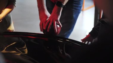 Araba kuaförü müzesinde arabaları inceleyen turistler. Ziyaretçiler aydınlanmış araç müzesi konseptinde lüks araba hakkında farklı ayrıntılara bakıyorlar