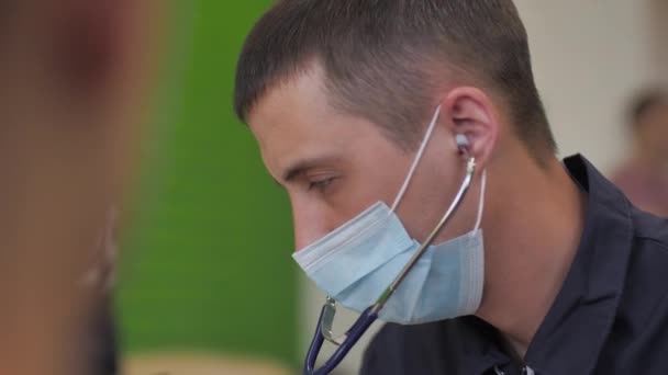アルマニー カザフスタン April 2023 保護マスクの男性医師は検査室で血圧をチェックします ドクター プラクティショナーがホッケー クラブの試験に参加 — ストック動画