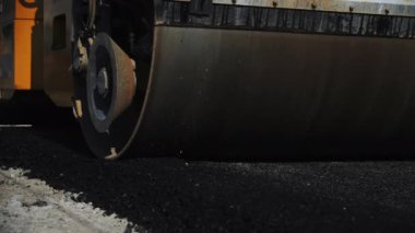 Asfalt sıkıştırıcı yolda beton kaplamasına basıyor. Paten kamyonu karayolu boyunca yol işlerinde sıcak karışım ile gider.