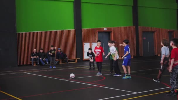アルゼンチン カザフスタン August 2023 スポーツウェアの子供チームは 学校の屋内ジムでサッカーをしています 熱狂的な若いプレーヤーはゴールスローモーションにボールを蹴るターンを取ります — ストック動画