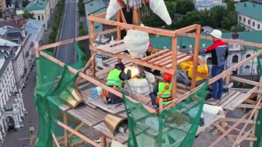 ALMATY, KAZAKHSTAN - 13 AĞUSTOS 2023: Büyük bir hassasiyetle inşaatçılar şehrin önde gelen yapısına beton yıldızı sıkıca iliştirirler. Çalışma ekibi özel malzeme ve vinç kullanıyor.