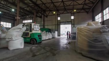 Forklift yükler ve depo kapısına taşır. Torbaları fabrikanın dışına taşıyan küçük kaldırma makinelerinin yan görüntüsü