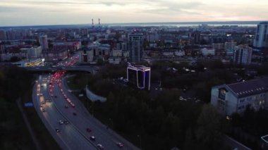 Arabaları ve üst geçitli köprüsü olan geniş yollu bir şehir yatağı. Aydınlatılmış gökdelen bina çevresi Alacakaranlık hava manzarası