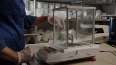 ALMATY, KAZAKHSTAN - EYLÜL 06 2023: Koruyucu eldivenli işçiler şeffaf pencereleri dikkatlice açarlar. Kişi, maddeleri tartmak için peçeteye kimyasal döker ve kompartımanı kapatır.