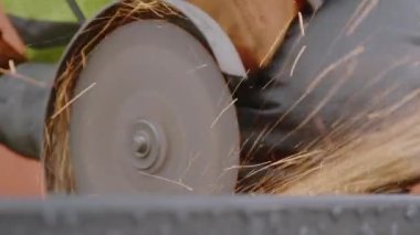 İnşaat alanında metal testereyi buharlı testereyle kesmek duşa yol açar. İşçi atölyede çeliği dairesel elektrikli aletle testereyle kesti