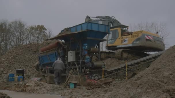 채석장을 찰흙에 그리고 굴착기를 거르기에 의하여 노동자 노동자는 구덩이에 기계를 — 비디오