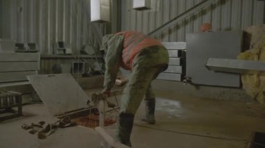 Çalışan, atölyedeki zemin kapağında uzaktan kumandalı nakliyeyi kontrol ediyor. İnşaatçı fabrika deposunda otomatik ekipmanla çalışıyor.