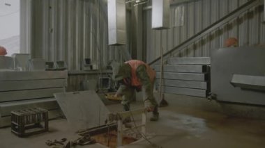 Uzaktan kumandalı bir çalışan zemin kapağına bakıyor. İnşaatçı fabrika deposu inşaatında ekipmanla çalışıyor.