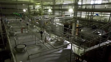 Fabrika atölyesindeki ince boru hatlarıyla bağlantılı kimyasalları işlemek için devasa metal tanklar. Fabrikada karışık reaksiyonlar için rezervuarlar