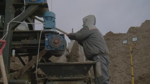 労働者はコンベヤー ベルトを運ぶ粘土のぬれた土からのローラーをきれいにします 労働者は鉱山採掘場の作業機構からぬれた鉱石を取り除きます — ストック動画