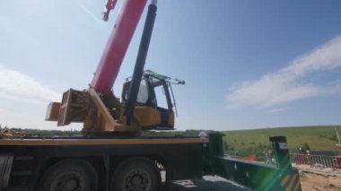 ALMATY, KAZAKHSTAN - 16 AĞUSTOS 2023: inşaat alanındaki kontrol kabininde yüksek vinç ve sürücü. İnşaatçı taşrada ağırlık kaldıran güçlü bir makine üzerinde çalışıyor.