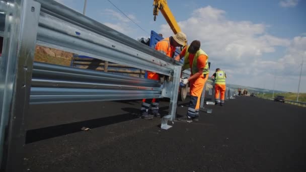 阿尔蒂 哈萨克斯坦 2023年8月16日 年轻工人在翻新后的高速公路上持有金属围栏部分 熟练的建筑商在公路建筑工地安装道路中线分隔边界 — 图库视频影像