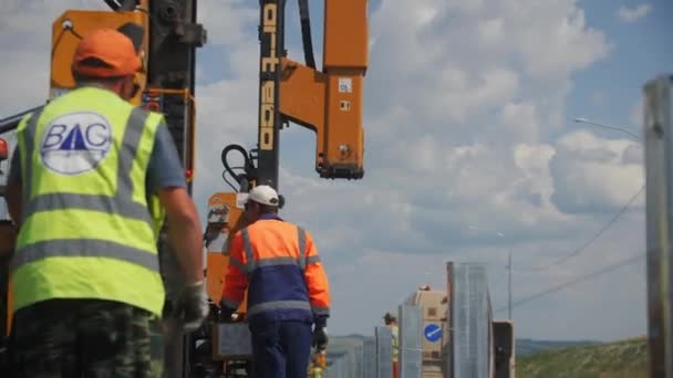 阿尔蒂 哈萨克斯坦 2023年8月16日 建筑商推着柴油锤子机走过道路上的金属杆 现代高速公路建筑工地的工人运输设备 — 图库视频影像