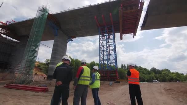 アルマニー Kazakhstan August 2023 エンジニアチームは 建設現場での交通橋の設置問題を議論しています スペシャリストが将来のオーバーパスブリッジセクションの下に立って話す — ストック動画