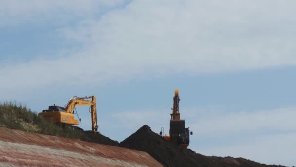 Almaty Kazakhstan 2023年8月16日 现代挖掘机将装有桶的土从山顶倾泻到路边斜坡上 挖泥机用铲子在建筑工地用轻云倾泻泥土 — 图库视频影像