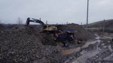 ALMATY, KAZAKHSTAN - 10 Ekim 2023: adam inşaat alanında kazıcı toprağı çalıştırıyor. İşçi, elek yapımcısının yanında duruyor. Malzemeyi ayıran özel makineyi kontrol ediyor.