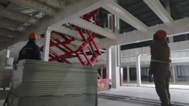 ALMATY, KAZAKHSTAN - 10 Ekim 2023: İşçiler sanayi parkındaki meslektaşlarının başka bir kata mal boşaltmasını bekliyorlar. Erkekler atölyede malları taşımak için yük asansörü kullanırlar.