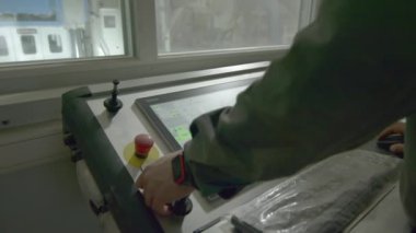 ALMATY, KAZAKHSTAN - 10 Ekim 2023: Endüstriyel park kontrolörünü kullanarak ekipman montaj makinesi çalıştırıyor. Operatör panel ekranında ekipman montaj sürecini kontrol eder