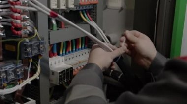 Mühendis endüstriyel parkta kabloları birbirine dolaştırıyor. İşçi depodaki kablolar arasında bağlantı kablosu kullanıyor.