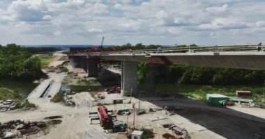 Nehir boyunca uzanan yol köprüsü inşaatı. Ağır ekipmanlı profesyonel işçilerin su üzerinde köprü inşa ettiği inşaat alanı