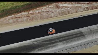 Asfalt silindirler yol inşaatı alanının hava manzarasında çalışır. Usta çalışanlar asfalt yüzeyi dışında özel makine kullanırlar.