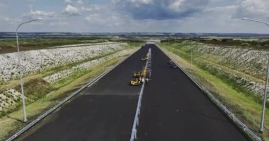 İşçiler kaza bariyeri için yolun ortasındaki yapıları onarıyor. Çalışanlar güvenlik inşaatı için özel makineler kullanıyorlar