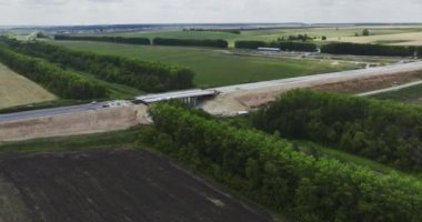 Köprü ile tarlaların ortasında uzun bir yol inşa etme süreci. Ormanlık arazide demiryolu üzerinde yol inşaatı