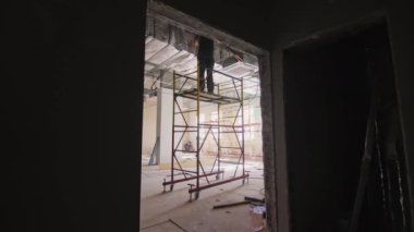 ALMATY, KAZAKHSTAN - 13 Şubat 2023: Su boru hattının güvenilirliğini kontrol eden inşaat işçisi. Becerikli işçiler odanın diğer tarafına boru döşüyorlar.