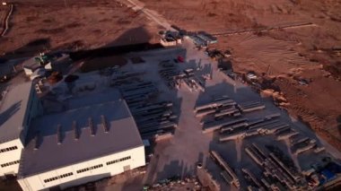 Endüstriyel parkın devasa üretim alanındaki yapılar. Uzak diyarlarda batan güneş altında sanayi binaları olan büyük bir arazi.